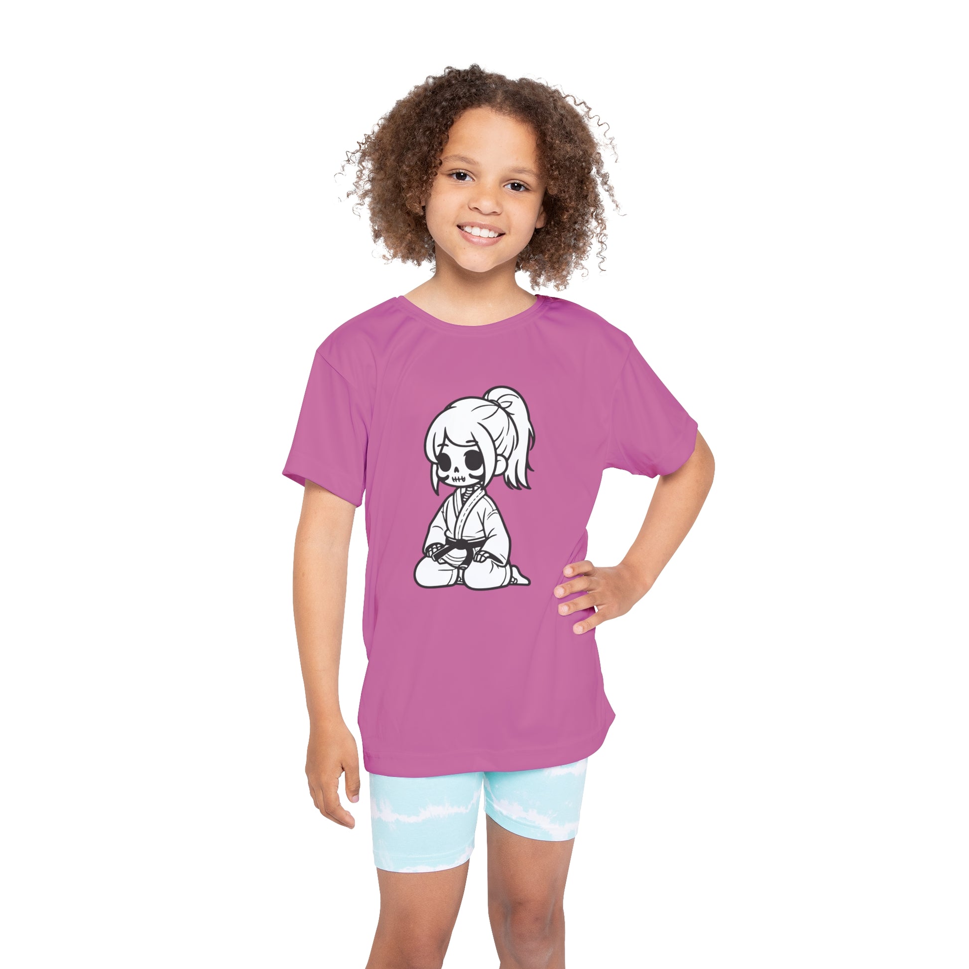 Front view of a girl wearing a light pink, polyester kids t-shirt, with a design of a skeleton girl wearing a jiu jitsu gi and black belt on the front.