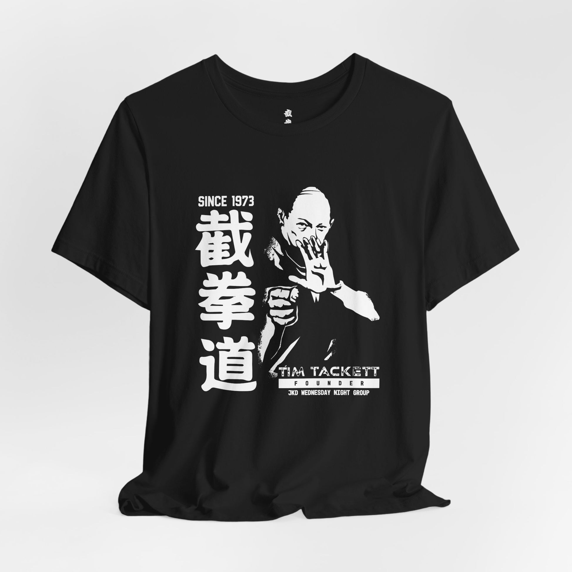 Alternate front view of a black cotton t-shirt, with an illustration of martial arts instructor Tim Tackett. The text surrounding the design reads "Jeet Kune Do since 1973".