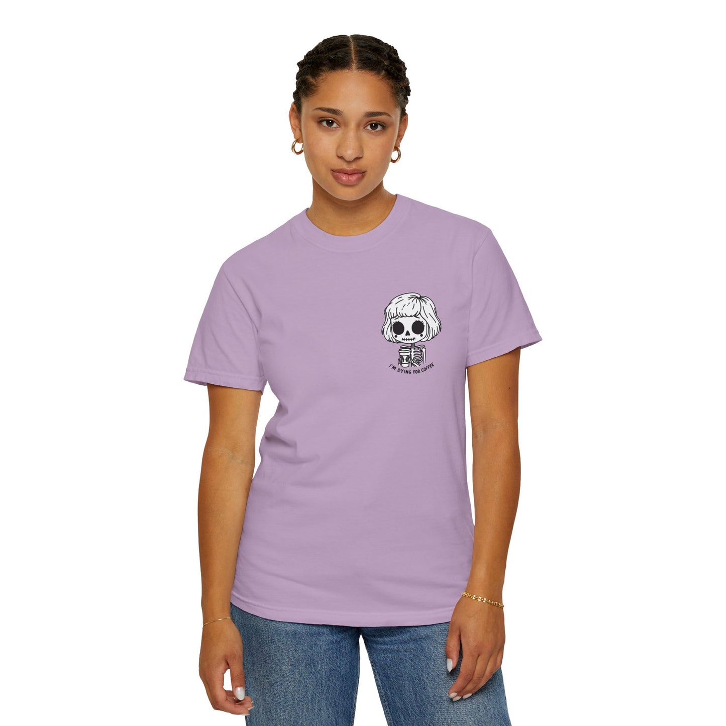 Alternate view of a woman wearing an Orchid colored t-shirt with a design of a skeleton girl holding a cup of coffee printed on the front. Written underneath the design is the text, "I'm dying for coffee". The design is placed on the left chest area of the t-shirt.