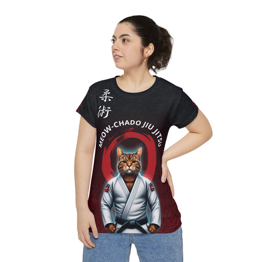 Woman wearing a black and red polyester, all over print t-shirt with an illustration of a cat wearing a Jiu Jitsu gi and black belt. Written above the cat is the text "Meow-Chado Jiu Jitsu". The sleeves of the shirt have claw marks across them.