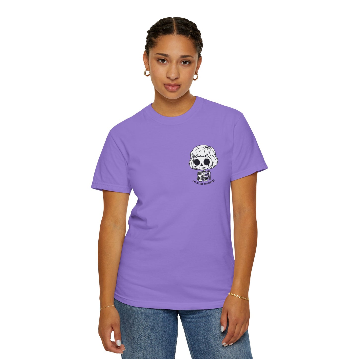 Alternate view of a woman wearing a Violet colored t-shirt with a design of a skeleton girl holding a cup of coffee printed on the front. Written underneath the design is the text, "I'm dying for coffee". The design is placed on the left chest area of the t-shirt.