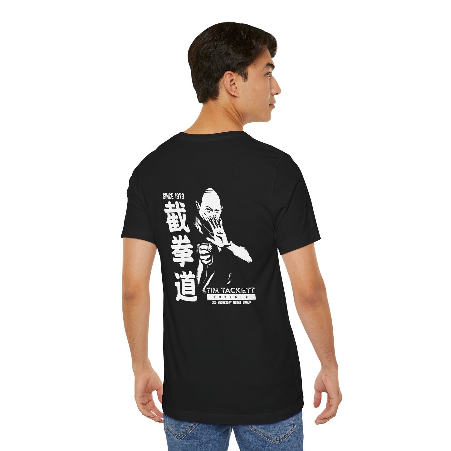 Man wearing a black cotton t-shirt, with an illustration of martial arts instructor Tim Tackett printed on the back.