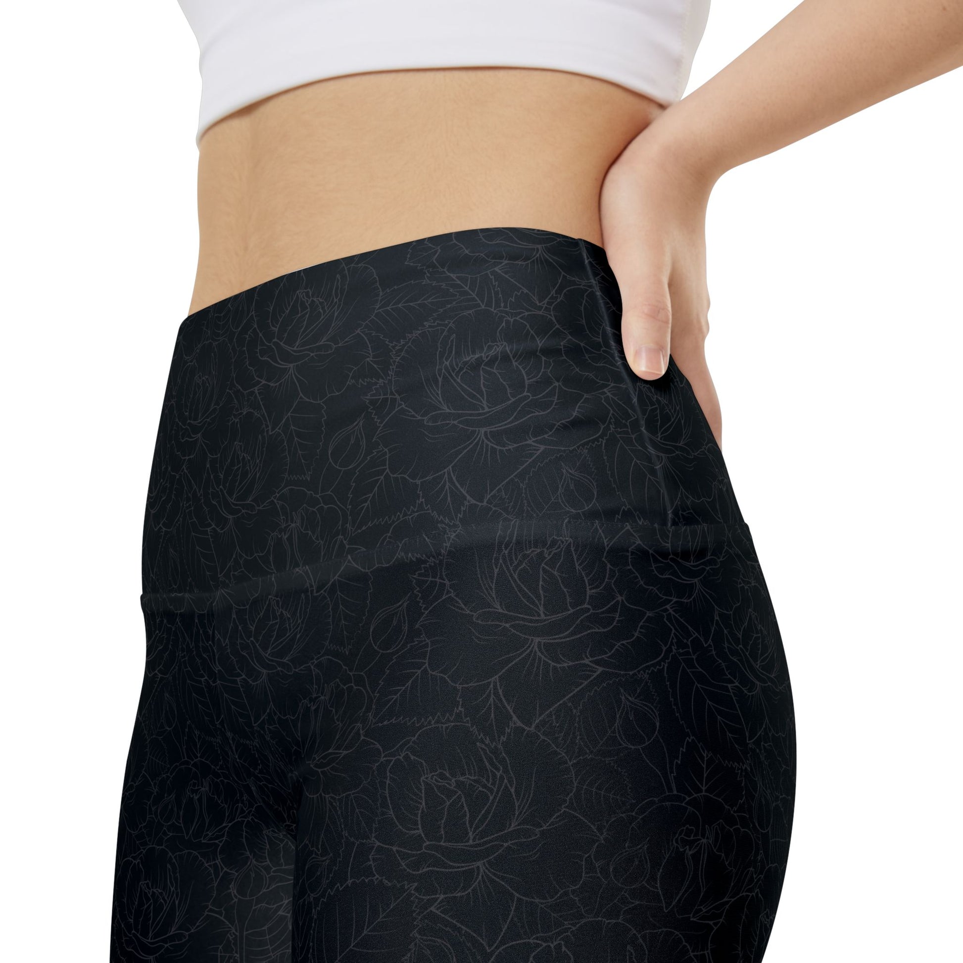 Close up, left side view of a woman wearing black, floral-patterned gym shorts with a high waist.