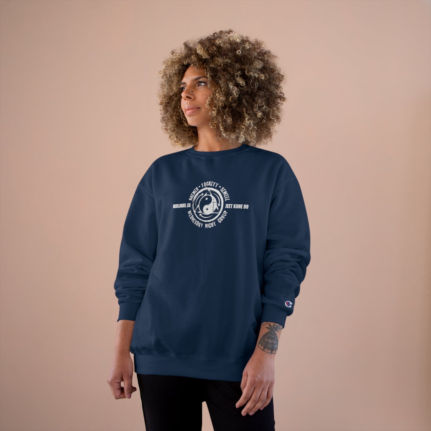 Woman wearing a navy colored, Champion brand sweatshirt, with the JKD Wednesday Night Group logo on the chest.