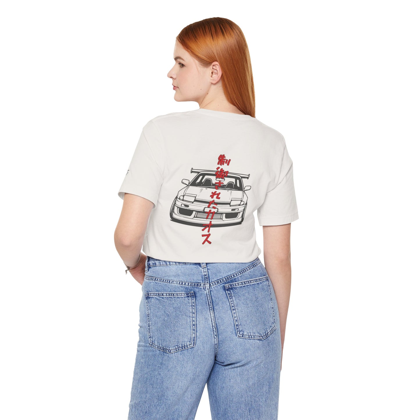 Back view of a woman wearing an off-white t-shirt with an illustration of a drift car, and the words "Controlled Chaos" written vertically in Japanese characters.