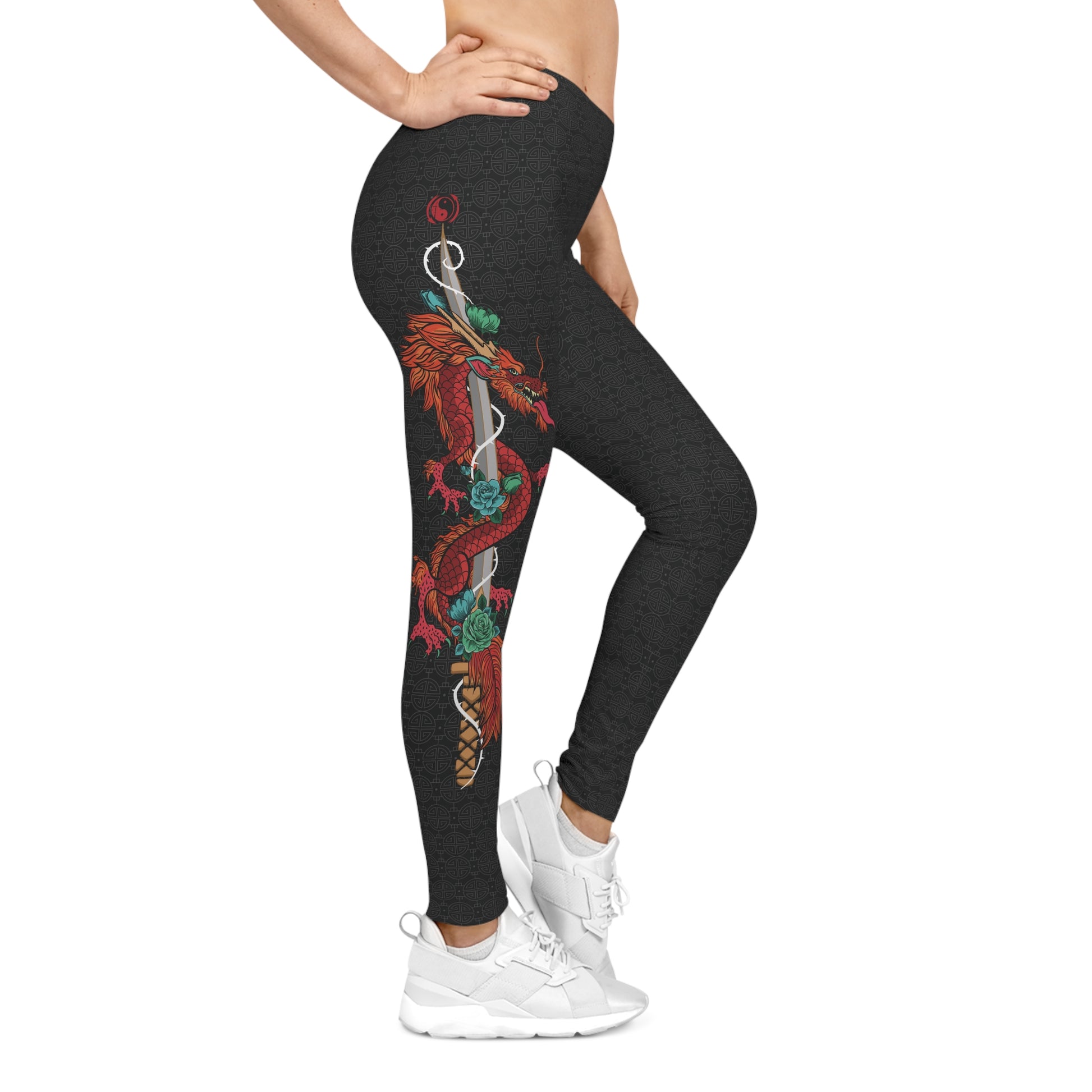 Right side view of black, patterned low-rise leggings, with a large design of a dragon wrapped around a sword. The design is placed vertically on the right leg.