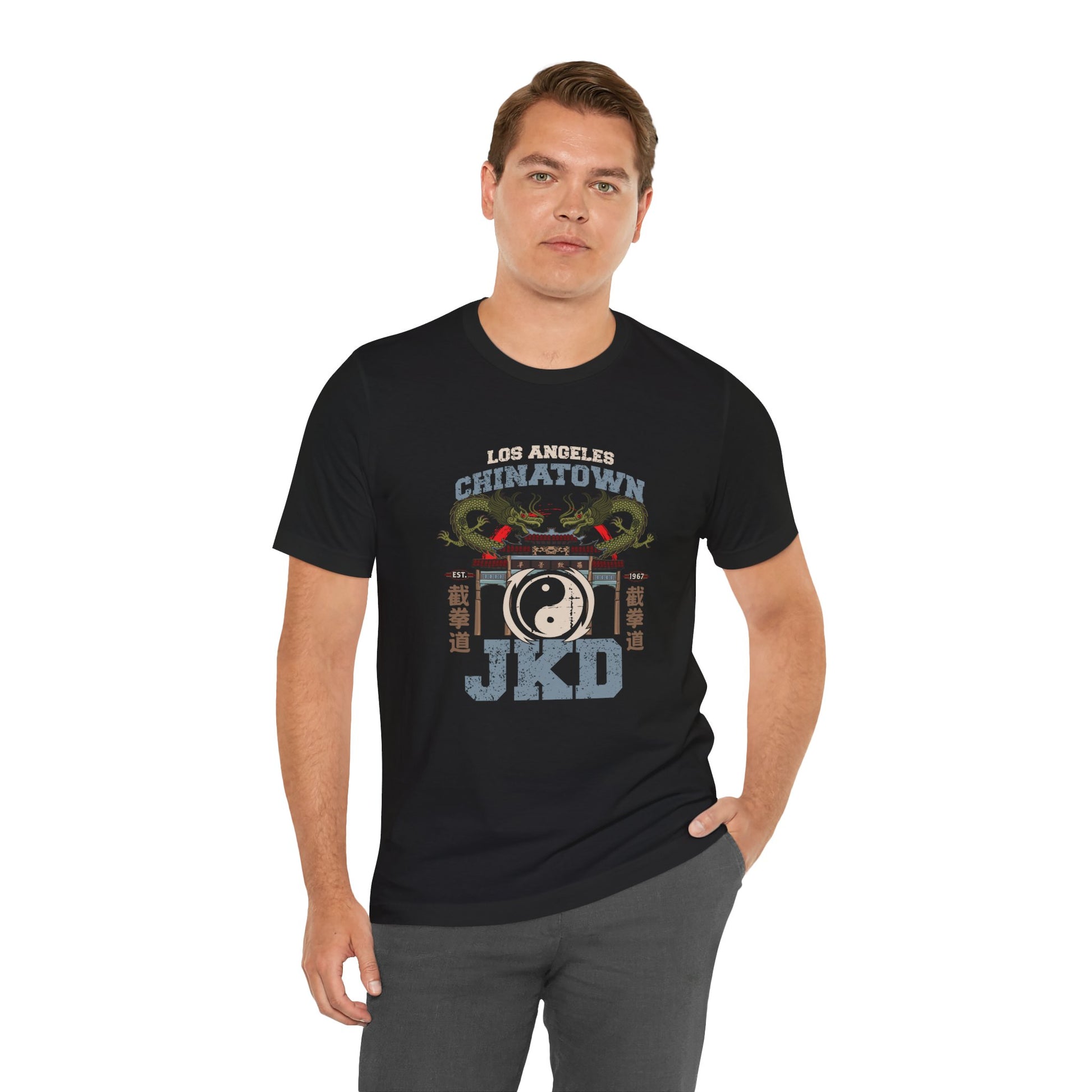 Alternate front view of a man wearing a black cotton t-shirt, with a design of twin dragons standing behind the L.A. Chinatown West Gate. The text above and below reads "Los Angeles Chinatown JKD". On the left and right sides are Chinese characters spelling Jeet Kune Do.