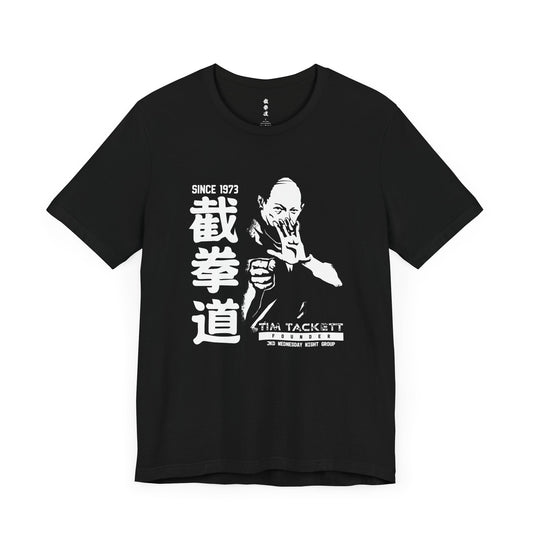 Front view of a black cotton t-shirt, with an illustration of martial arts instructor Tim Tackett. The text surrounding the design reads "Jeet Kune Do since 1973".