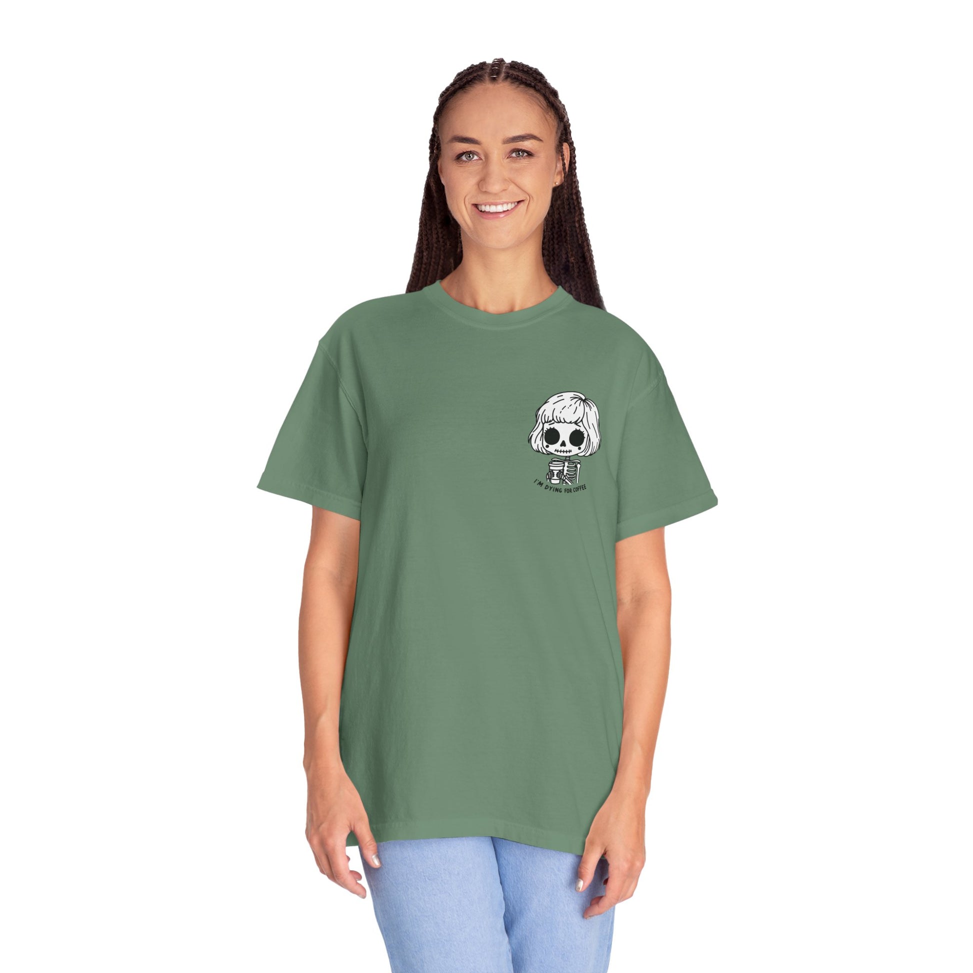 Alternate view of a tall, thin woman wearing a Light Green colored t-shirt with a design of a skeleton girl holding a cup of coffee printed on the front. Written underneath the design is the text, "I'm dying for coffee". The design is placed on the left chest area of the t-shirt.