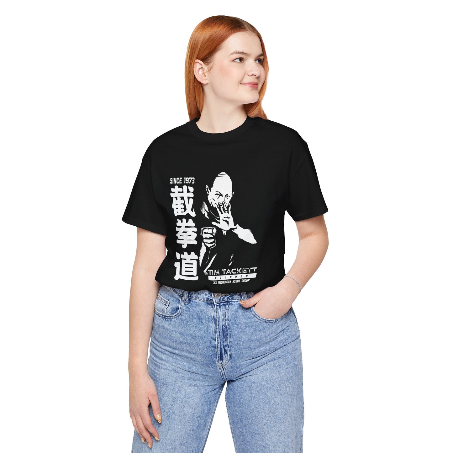 Woman wearing a black cotton t-shirt, with an illustration of martial arts instructor Tim Tackett. The text surrounding the design reads "Jeet Kune Do since 1973".