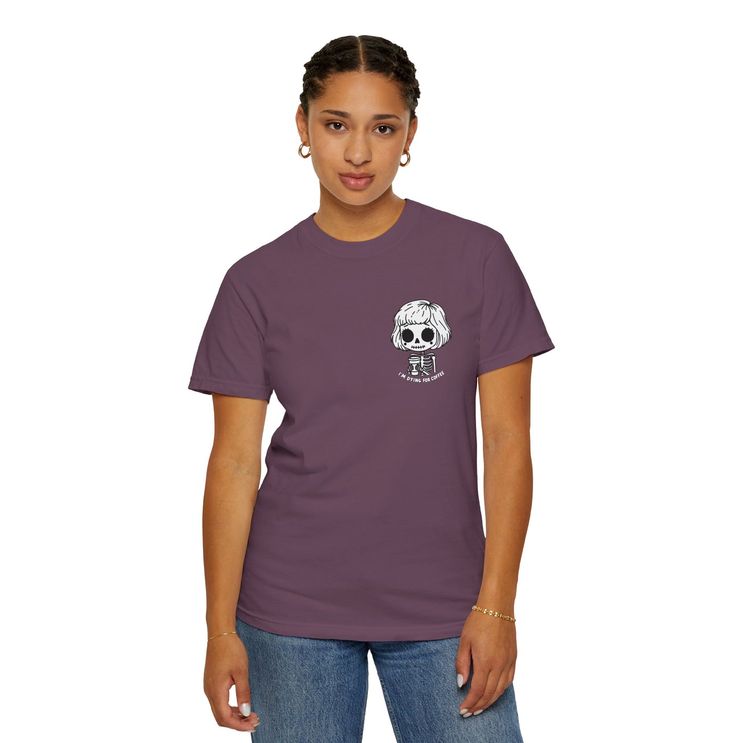 Woman wearing a berry colored t-shirt with a design of a skeleton girl holding a cup of coffee. Written underneath is the text "I'm dying for coffee". The design is placed on the left chest area of the t-shirt.