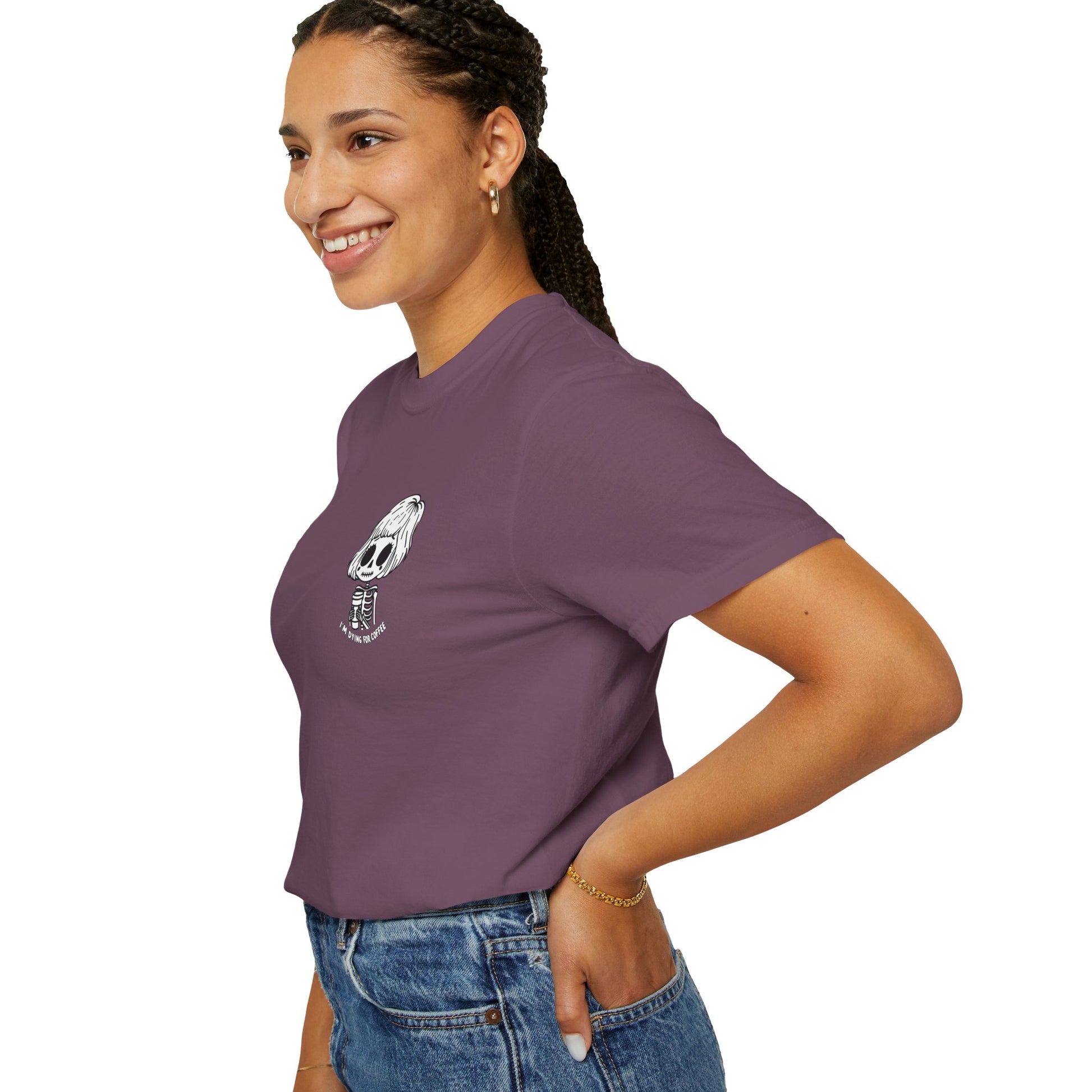 Left side view of a woman wearing a berry colored t-shirt with a design of a skeleton girl holding a cup of coffee. Written underneath is the text "I'm dying for coffee". The design is placed on the left chest area of the t-shirt.