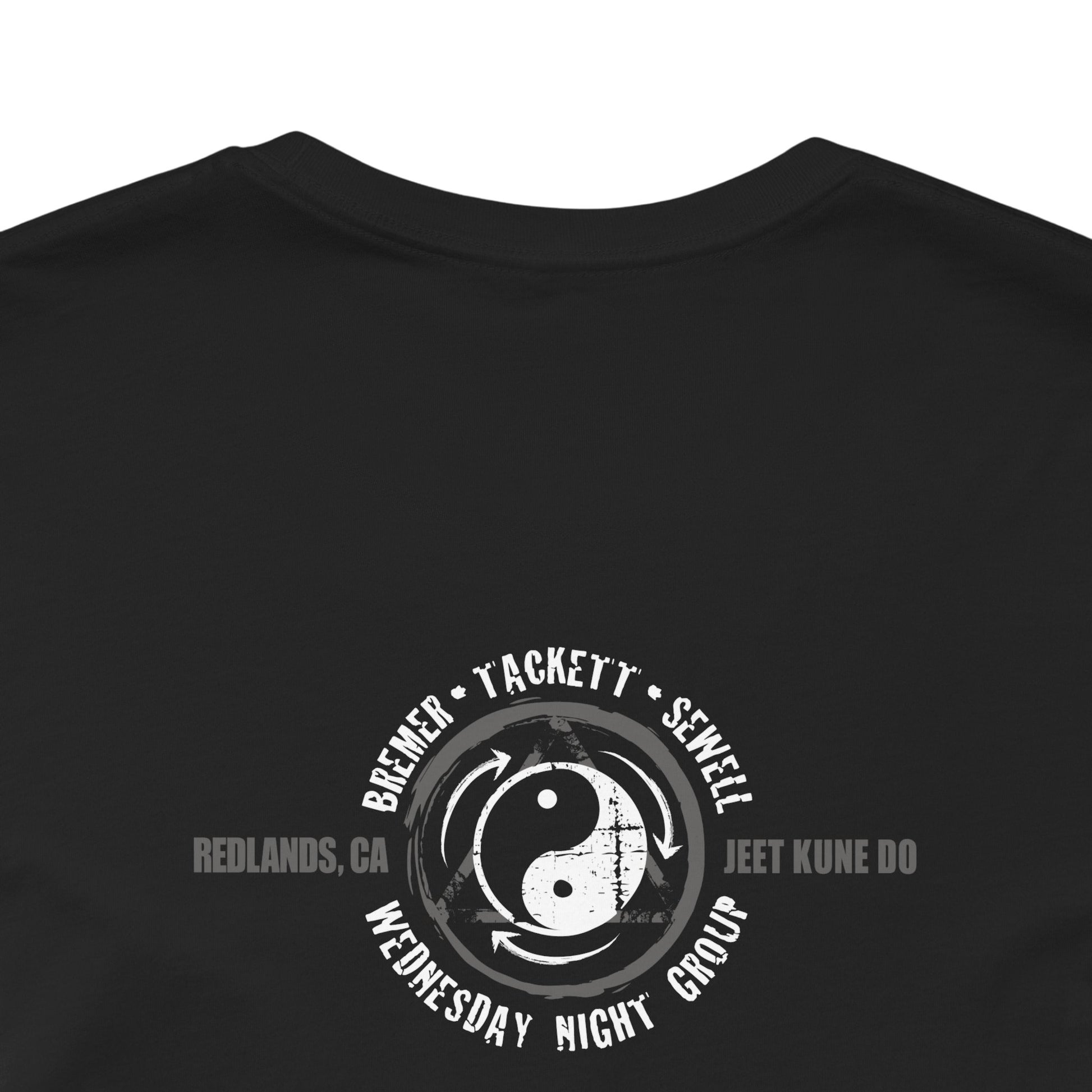 Close up view of the back of a black cotton t-shirt, featuring the JKD Wednesday NIght Group logo.