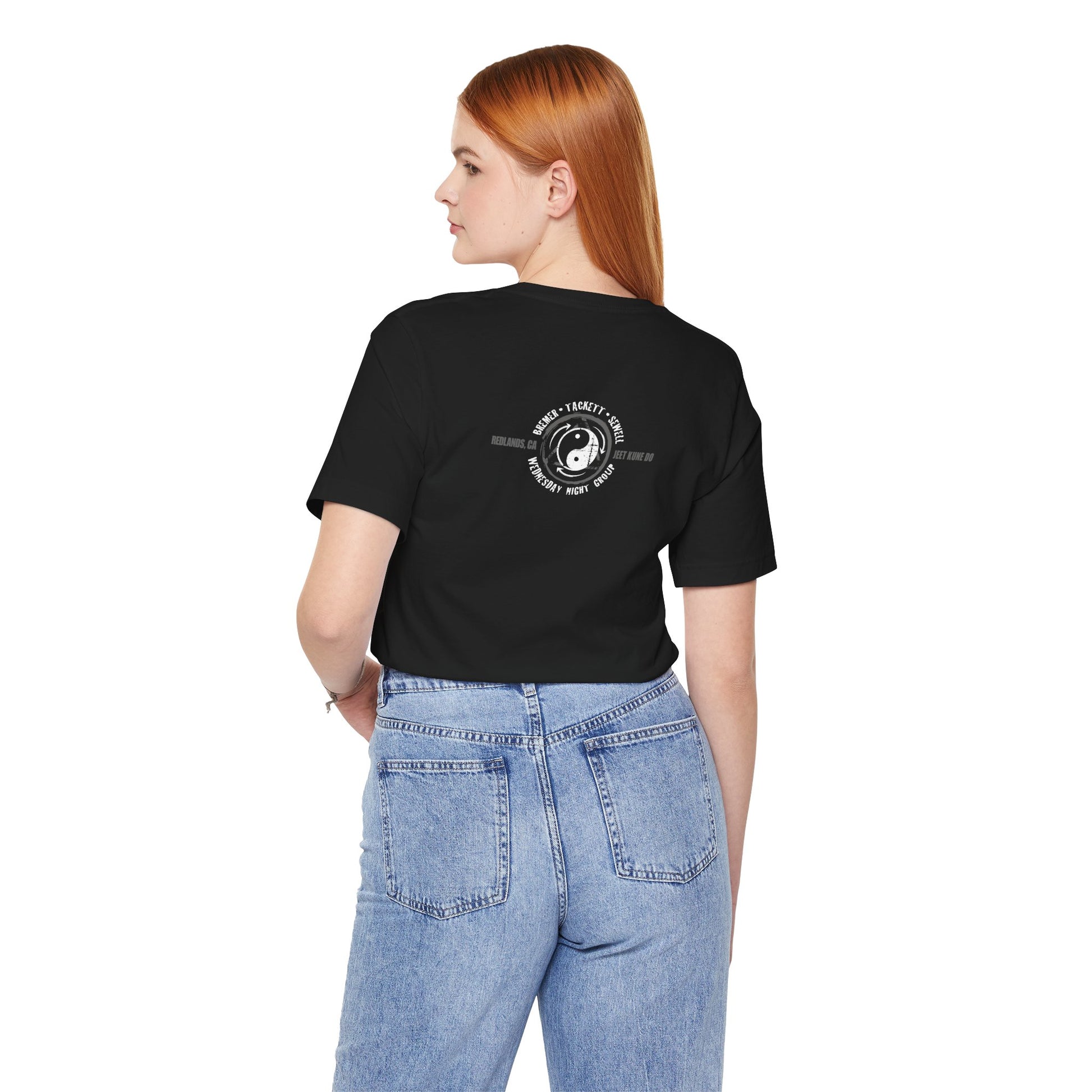 Back view of a woman wearing a black cotton t-shirt, featuring the JKD Wednesday Night Group logo.