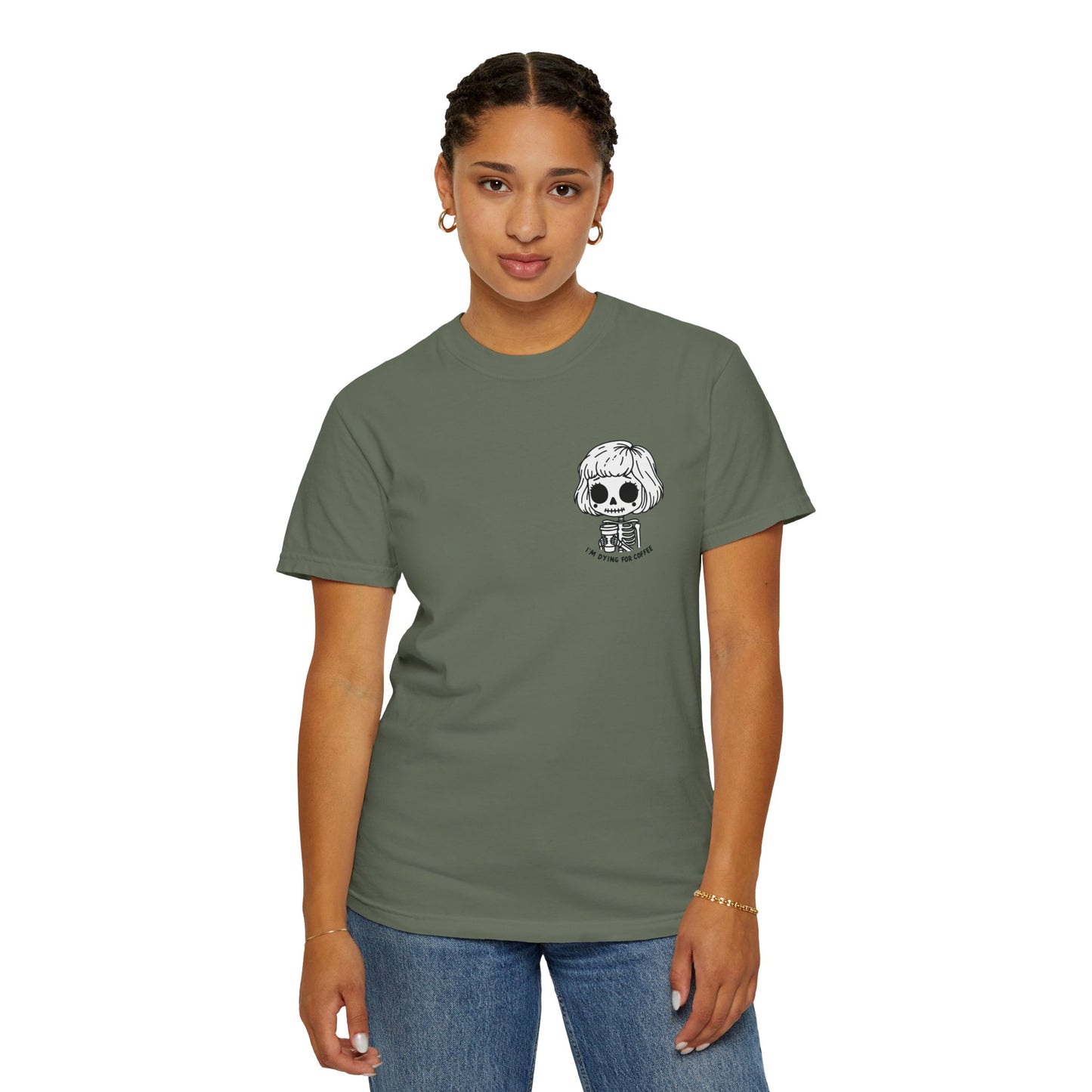 Alternate view of a woman wearing a Moss colored t-shirt with a design of a skeleton girl holding a cup of coffee printed on the front. Written underneath the design is the text, "I'm dying for coffee". The design is placed on the left chest area of the t-shirt.