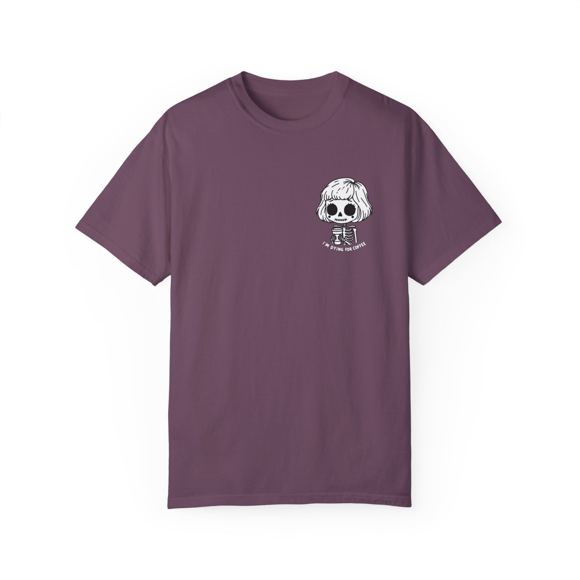 Front view of a berry colored t-shirt with a design of a skeleton girl holding a cup of coffee. Written underneath the design is the text, "I'm dying for coffee". The design is placed on the left chest area of the t-shirt.