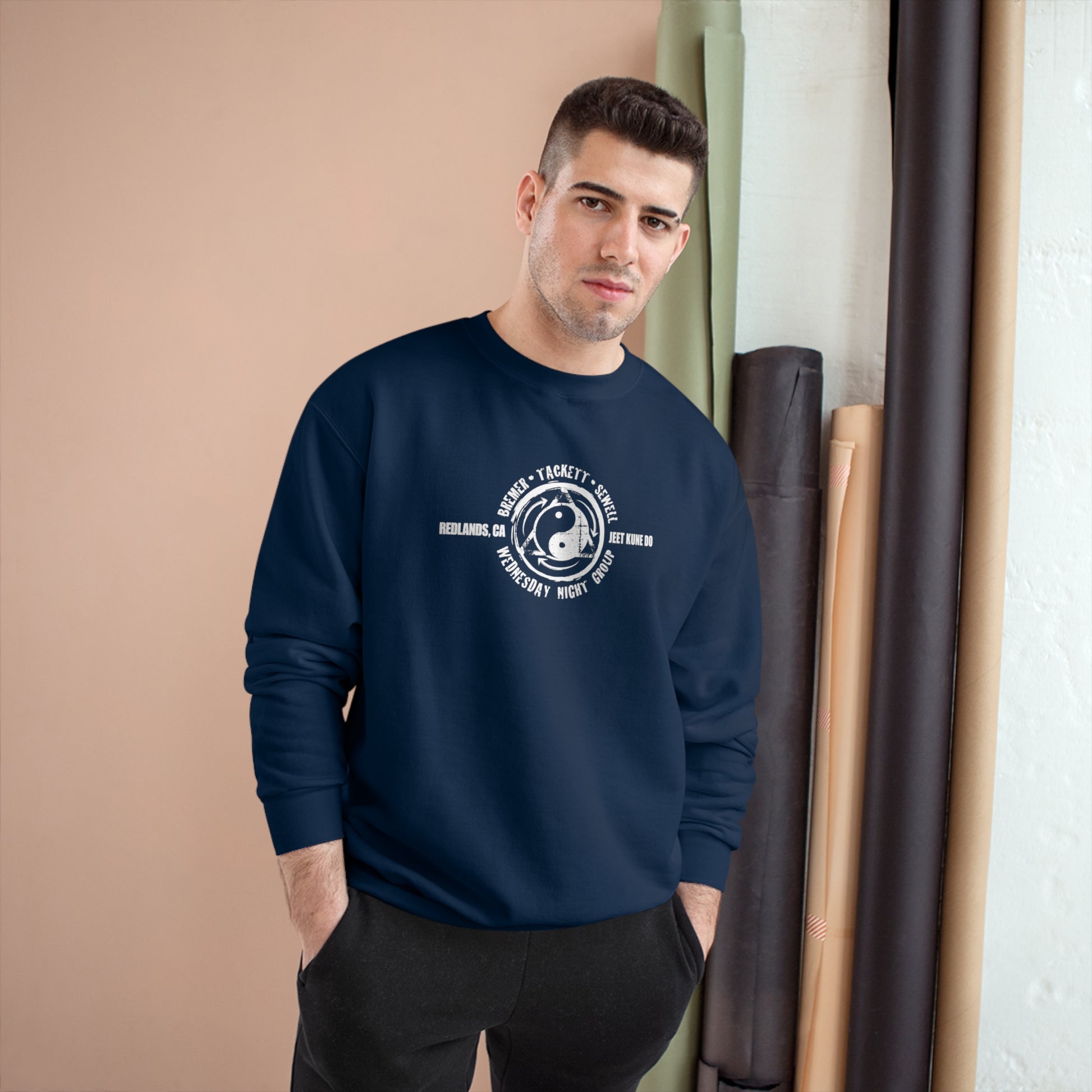 Man wearing a navy colored, Champion brand sweatshirt, with the JKD Wednesday Night Group logo on the chest.