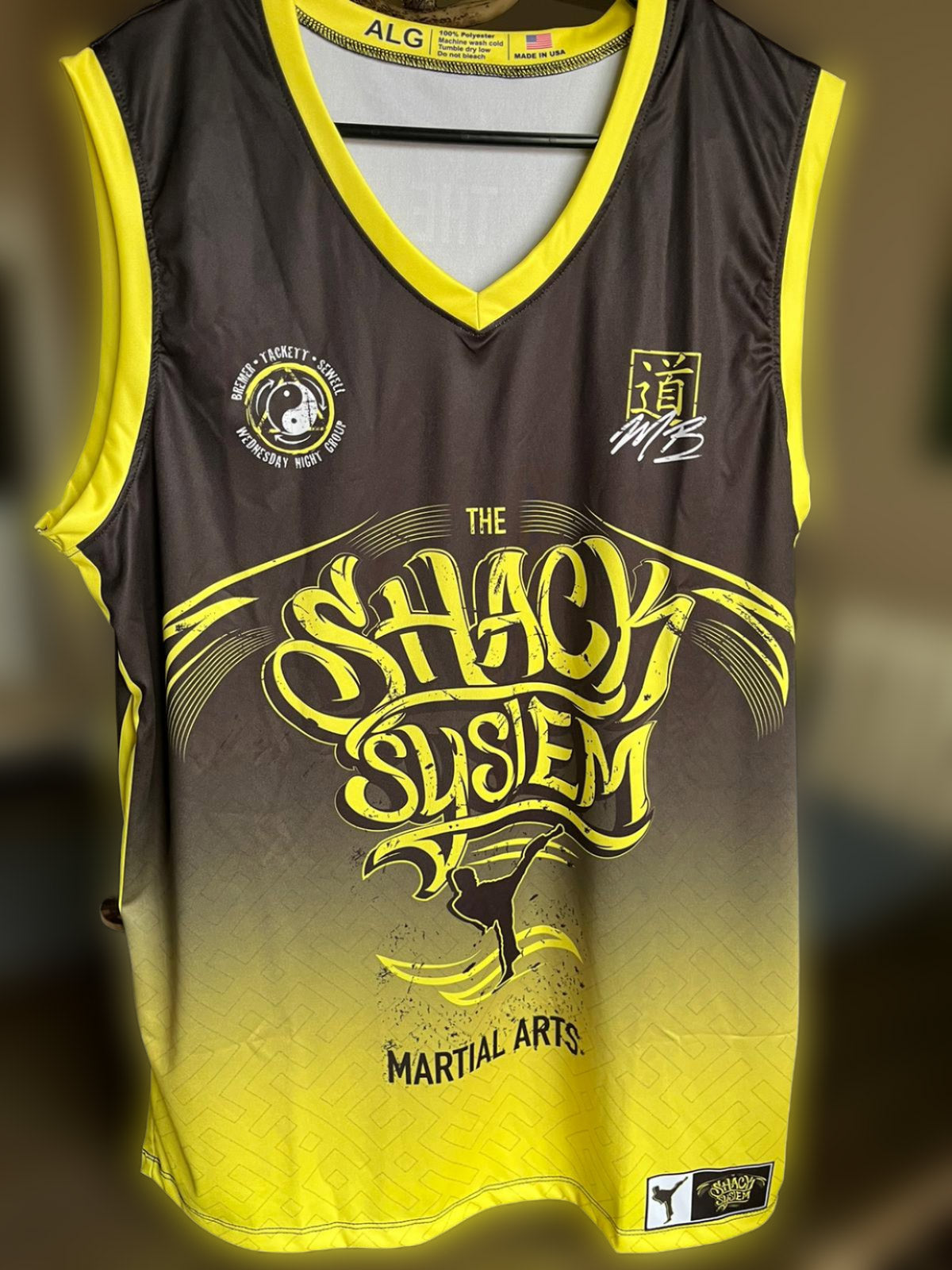 A black and yellow custom Muay Thai jersey with The Shack System logo on the front.