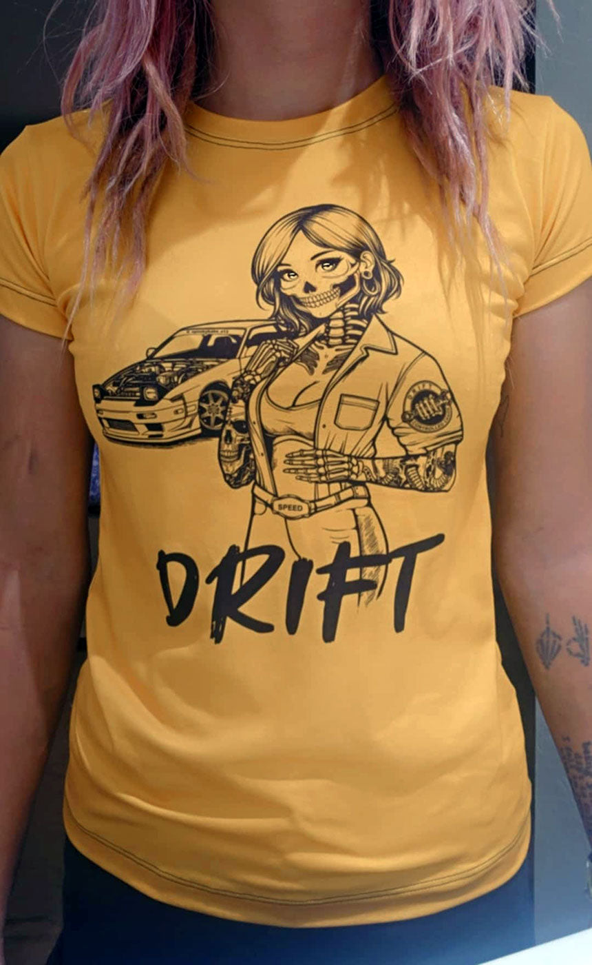 Woman wearing a yellow, polyester blend t-shirt with a design of a female skeleton dressed as a mechanic. The mechanic is standing next to her car with the word "Drift" written underneath.