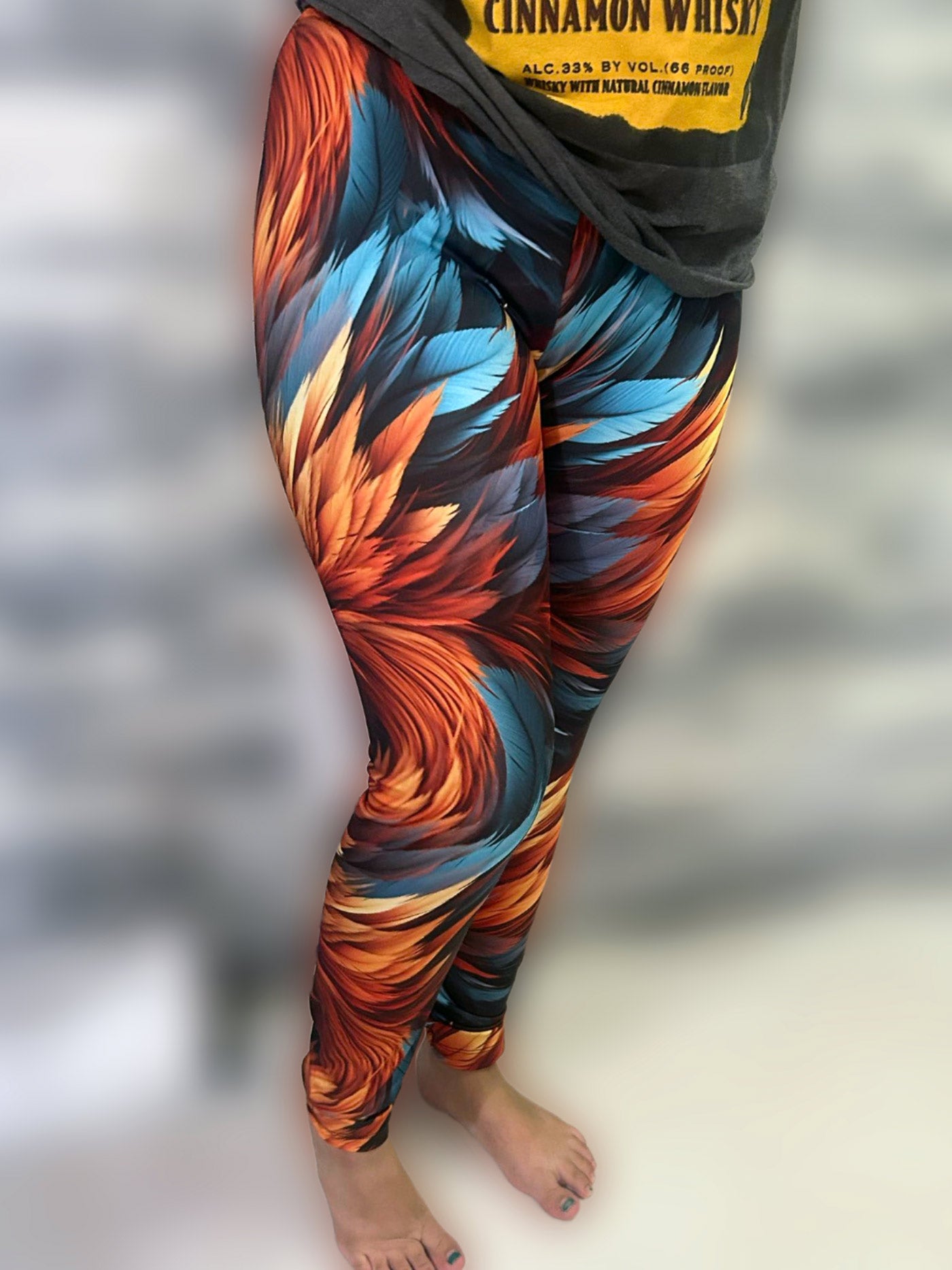 Woman wearing aqua and orange colored, feather print low rise leggings.