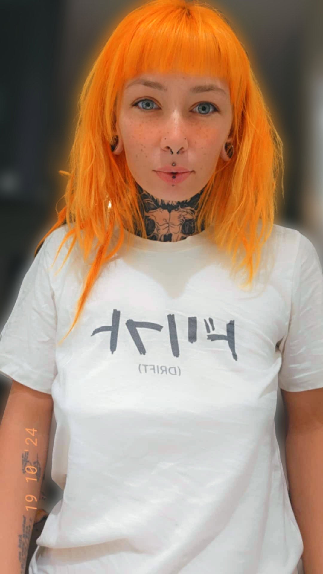 Mirror selfie of a woman wearing an off-white t-shirt with text printed on the chest that spells Drift in Japanese.